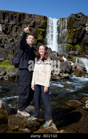 Un jeune couple traversant un ruisseau de montagne tandis que dehors à marcher ensemble tourné sur place en Islande Banque D'Images