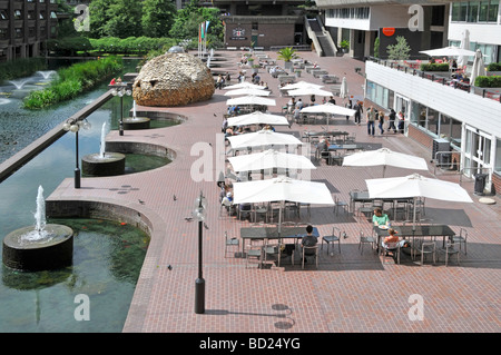 Barbican Centre terrasses au bord du lac avec des gens mangeant à l'extérieur à des tables et des chaises au bord de l'eau sous des parasols d'été blancs City of London Angleterre UK Banque D'Images