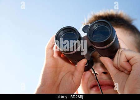 Garçon de dix ans regarde à travers des jumelles de jouets au Royaume-Uni Banque D'Images