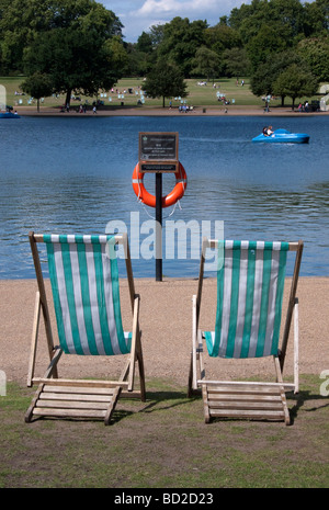 Transats autour de la Serpentine dans Hyde Park London UK Banque D'Images