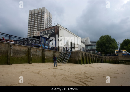 Un garçon joue sur la plage de la Tamise à marée basse avec Gabriel's Wharf et Kent House (QG d'ITV) en arrière-plan. Banque D'Images