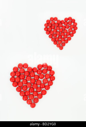 La vie toujours tourné artistique de l'ensemble des bonbons rouges en deux formes coeur prises sur un fond blanc. Banque D'Images