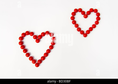 La vie toujours tourné artistique de l'ensemble des bonbons rouges en deux formes coeur prises sur un fond blanc. Banque D'Images
