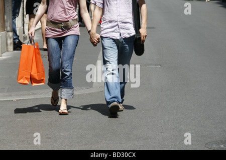 Young couple holding hands walking in town Banque D'Images