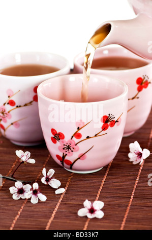 Verser le thé vert dans des tasses avec cherry blossom design Banque D'Images