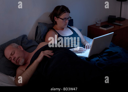 L'homme et la femme au lit peut accueillir l'homme femme travaille sur son ordinateur portable Banque D'Images