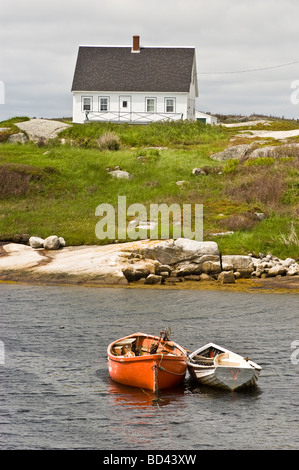 Deux petits bateaux flottant dans l'eau près d'une maison de pêcheur dans le port de Peggy's Cove, Halifax, Nouvelle-Écosse, Canada. Banque D'Images