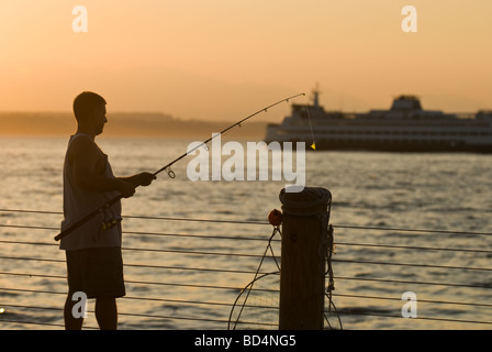 Un homme poissons au large de la jetée à Alki Beach Park à Seattle. Banque D'Images