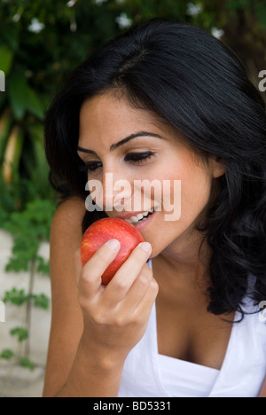 Belle jeune femme mangeant une pomme fruit rouge en plein air Liban Moyen Orient Banque D'Images