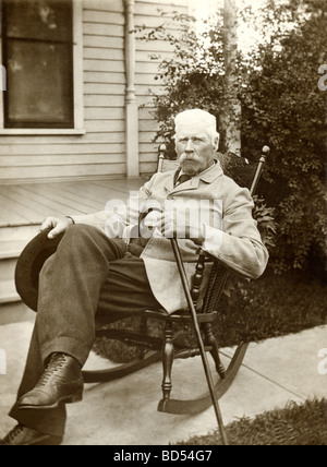 Stern vieil homme dans un fauteuil à bascule sur le trottoir Banque D'Images