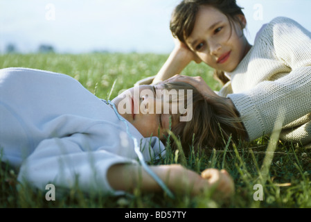 Soeur et frère couché ensemble dans l'herbe, girl touching dormir tête du garçon Banque D'Images