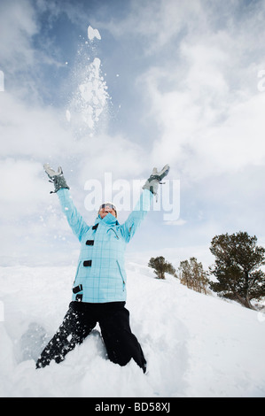 A woman throwing snow jusqu'à l'air Banque D'Images