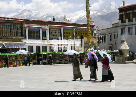 Trois femmes tibétaines locales avec des parasols pour protéger du soleil traversant quartier du Barkhor à Lhassa Banque D'Images