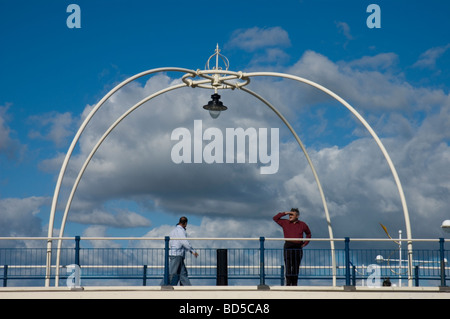 Un homme se protège les yeux du soleil comme il l'analyse de la plage de Southport pier Banque D'Images