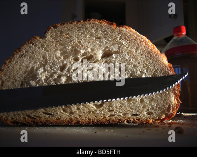 Un couteau dentelé repose en face d'une miche de pain croûté au four pain artisanal Banque D'Images