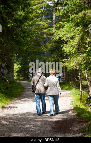Couple en train de marcher le long d'un sentier de forêt à travers les arbres Banque D'Images