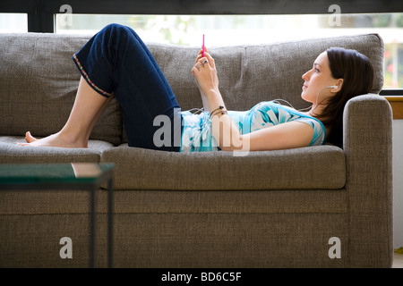 Femme sur canapé à l'écoute de son Ipod Banque D'Images