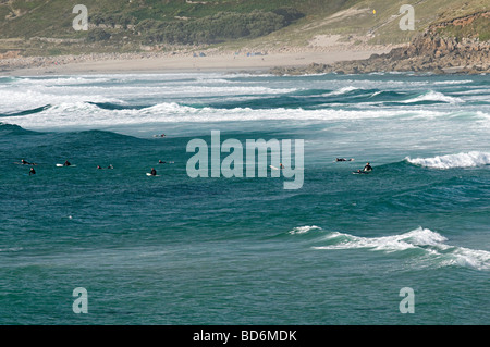 Surfeurs de sennen cove cornwall assis dans l'eau en attente d'une bonne vague Banque D'Images