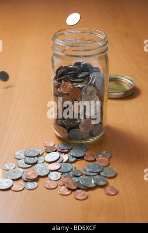 Laissant tomber des pièces de monnaie dans un pot Banque D'Images