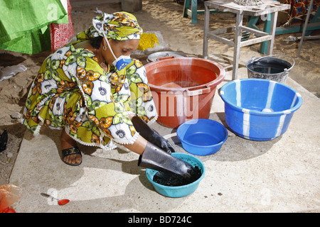 Femme portant un masque respiratoire, tout en mélangeant les couleurs pour la teinture batik, travail à domicile, Maroua, Cameroun, Afrique Banque D'Images