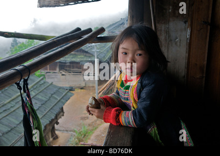 Petite fille Miao Basha dans la véranda de la maison de village du comté de Congjiang Guizhou Province Chine Banque D'Images