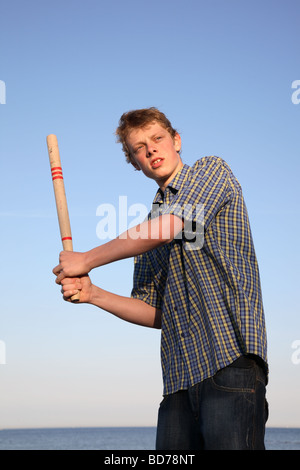 Teenage boy holding a bat prêt à frapper la balle dans un jeu de rounders. Banque D'Images