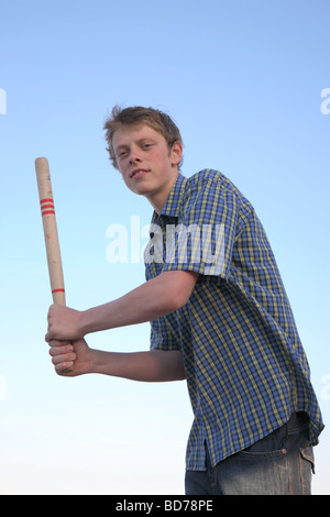 Teenage boy holding a bat prêt à frapper la balle dans un jeu de rounders. Banque D'Images