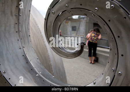 Femme avec enfant regarde l'échelle à poissons par les vagues du saumon de la sculpture à l'Hiram M Chittenden Locks, Ballard, Seattle. Banque D'Images