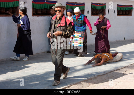 Bodhnath, au Népal. Un bouddhiste dévot Cherche le mérite, bénédictions et le pardon en entourant le stupa dans une série de prosternations. Banque D'Images