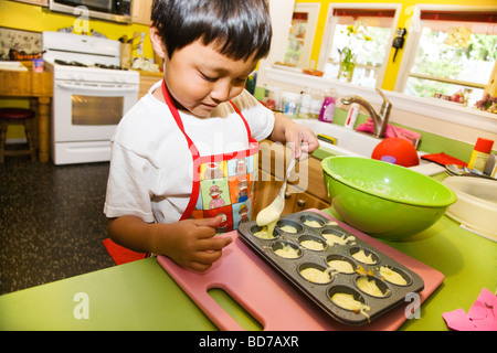 Jeune garçon faisant cupcakes Banque D'Images