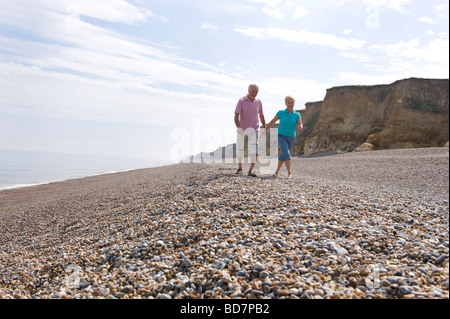 Mature couple walking sur plage de galets Banque D'Images