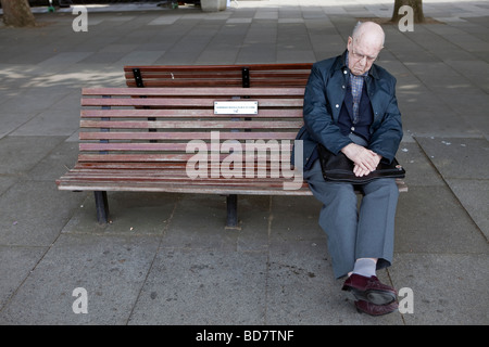 Un homme âgé se repose tandis qu'assis sur un banc. Banque D'Images