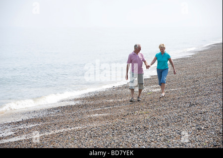 Mature couple walking sur plage de galets Banque D'Images