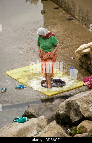 Femme marocaine lave la façon traditionnelle jusqu'à la rivière qui traverse Chefchaouen Banque D'Images