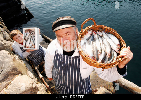 Dan le fishman Garnett et fils va avec certaines prises sur l'offre de festivaliers au festival annuel du hareng Clovelly Banque D'Images