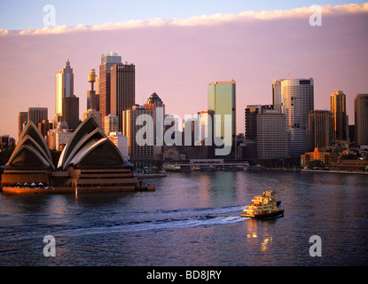 Des taxis bateau traversant le Port de Sydney avec l'Opéra et de la skyline at dawn Banque D'Images