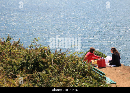 Deux femmes de manger sur le bord de la falaise avec une vue sur la mer près de Jerbourg Point Guernsey Channel Islands Banque D'Images