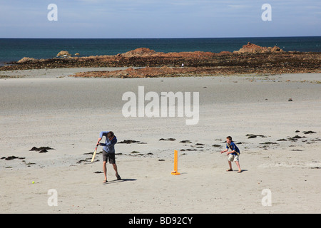 L'homme et un garçon à jouer au cricket sur la plage de grandes Rocques, Guernsey, Channel Islands Banque D'Images