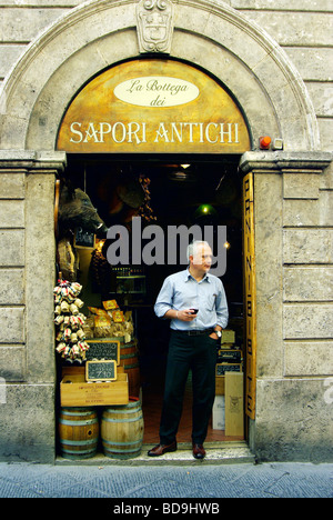 L'homme se trouve à l'extérieur (enoteca wine shop) et supérette appelée "vieilles saveurs', tenant un verre de vin rouge à Pitigliano Banque D'Images