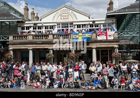 Des foules de touristes/personnes regardant un artiste de rue en face de la Pub Punch and Judy occupé au marché de Covent Garden, Londres Banque D'Images