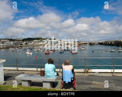 Une femme assise et un homme dans un fauteuil roulant vue sur St Peter Port Guernsey Channel Islands Pot Banque D'Images