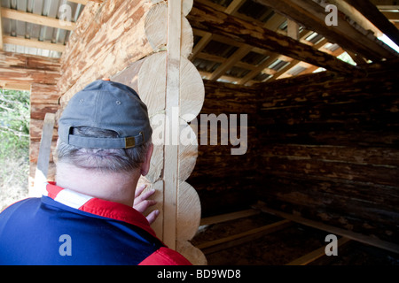 Homme âgé contrôlant l'encadrement de porte d'une cabine en rondins , Finlande Banque D'Images