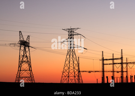 La silhouette des pylônes électriques contre un ciel rouge au coucher du soleil Banque D'Images