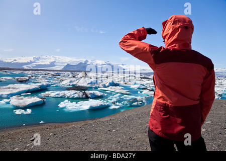 Female hiker à l'ensemble de l'Iceberg Lagoon Islande Jokulsarlon glacial rempli d'Icebergs. Banque D'Images