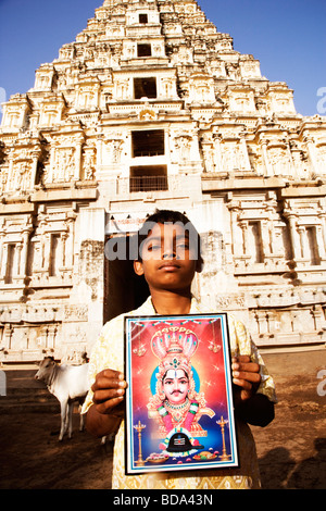 Portrait of a Boy holding a d'image de Dieu en face d'un temple, temple de Virupaksha, Hampi, Karnataka, Inde Banque D'Images