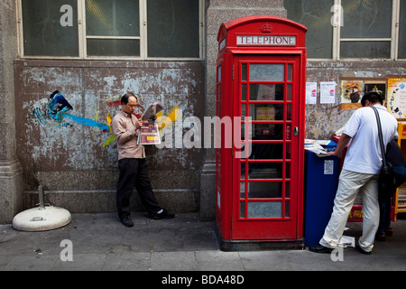 Scène dans le quartier chinois de Londres sur la rue Gerrard. Un homme lit un journal chinois locaux gratuits Banque D'Images