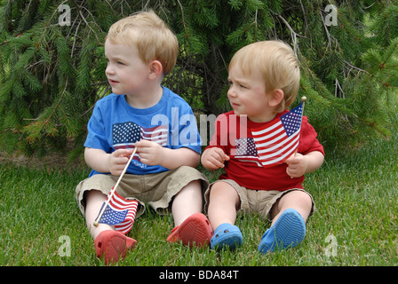 Deux frères célébrer le quatrième de juillet à il y patriotic rouge, blanc, et bleu ils leurs tenues de vague des drapeaux américains. L'un est un Banque D'Images