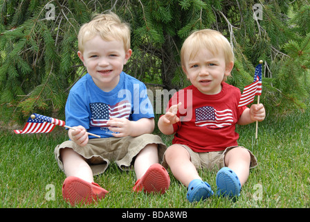 Deux frères célébrer le quatrième de juillet à il y patriotic rouge, blanc, et bleu ils leurs tenues de vague des drapeaux américains. Banque D'Images