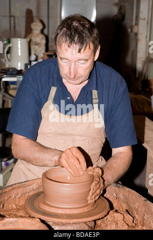 Potter au travail tournant un pot sur une roue de potier. Banque D'Images