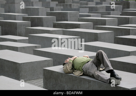 Un visiteur se repose dans la contemplation sur une dalle au Mémorial aux Juifs assassinés d'Europe à Berlin, Allemagne Banque D'Images